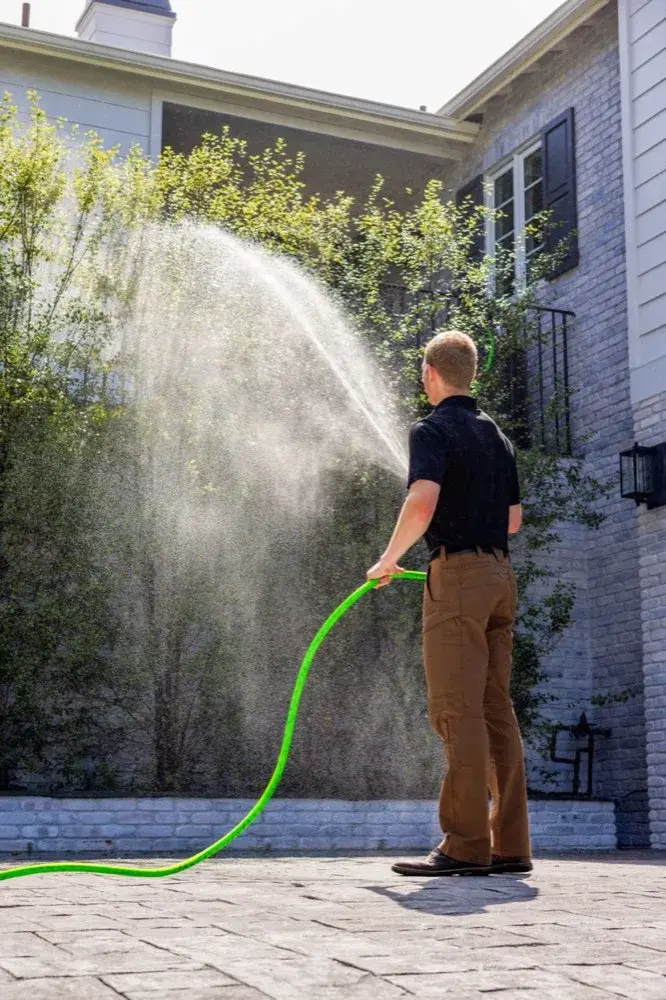 Technician spraying Matador Fire retardant onto landscaping with the system hose
